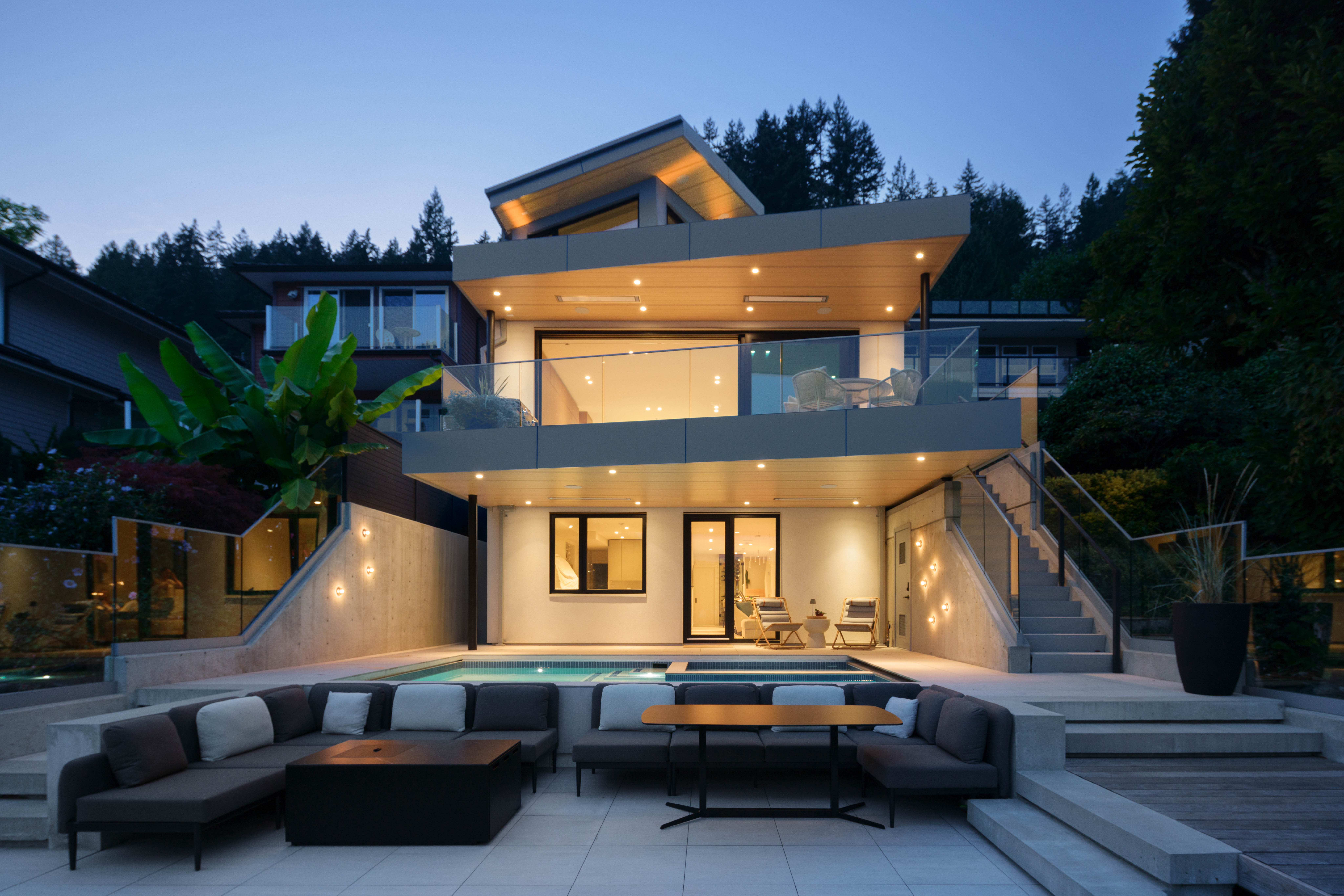 Fala waterfront custom home rear exterior at dusk with pool and outdoor living area