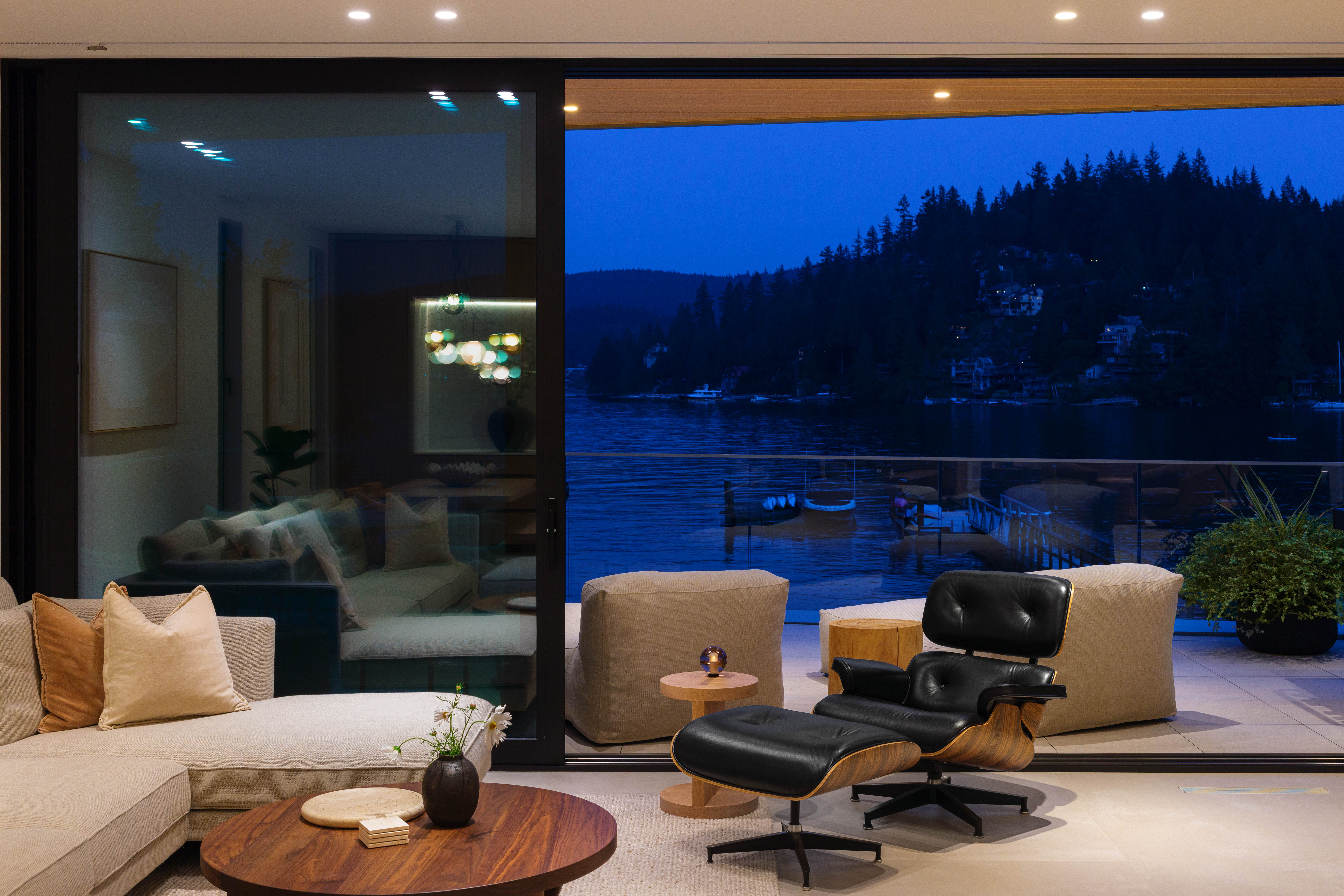 Fala custom home living room with waterfront views at dusk