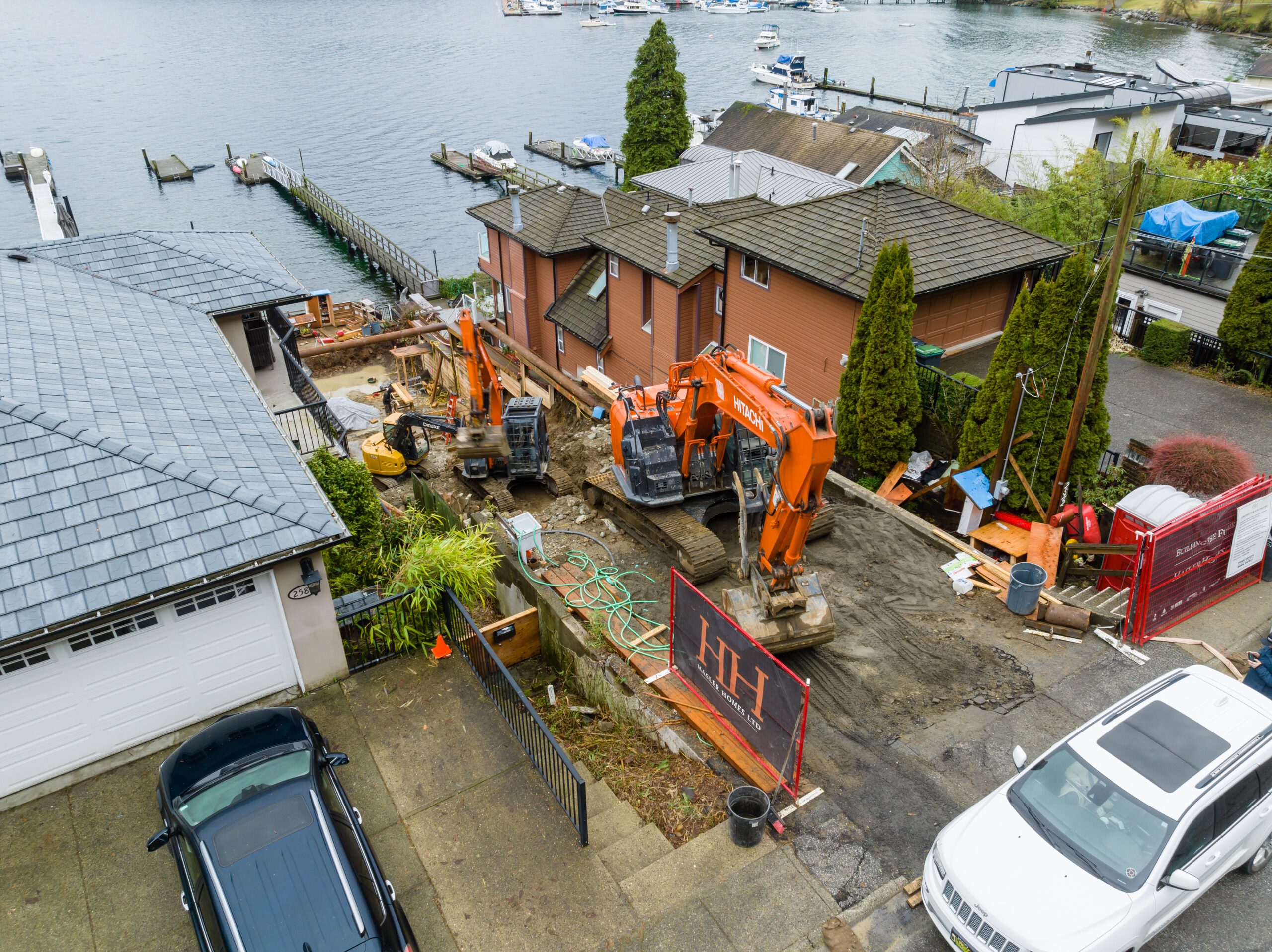 Excavators preparing a steep waterfront lot for custom home construction in North Vancouver.