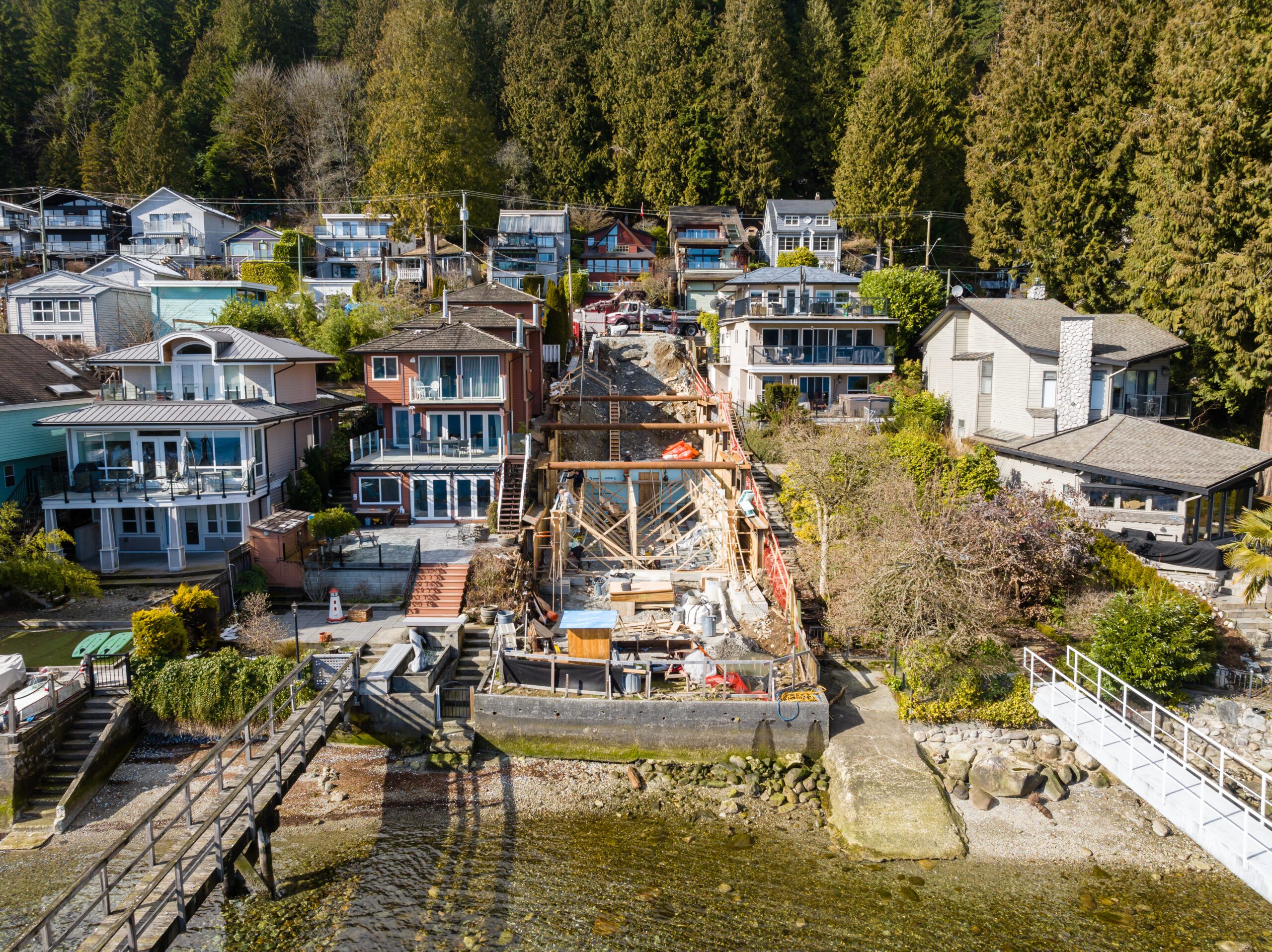Foundation and structural framing under construction for a custom home on a steep slope in Deep Cove.