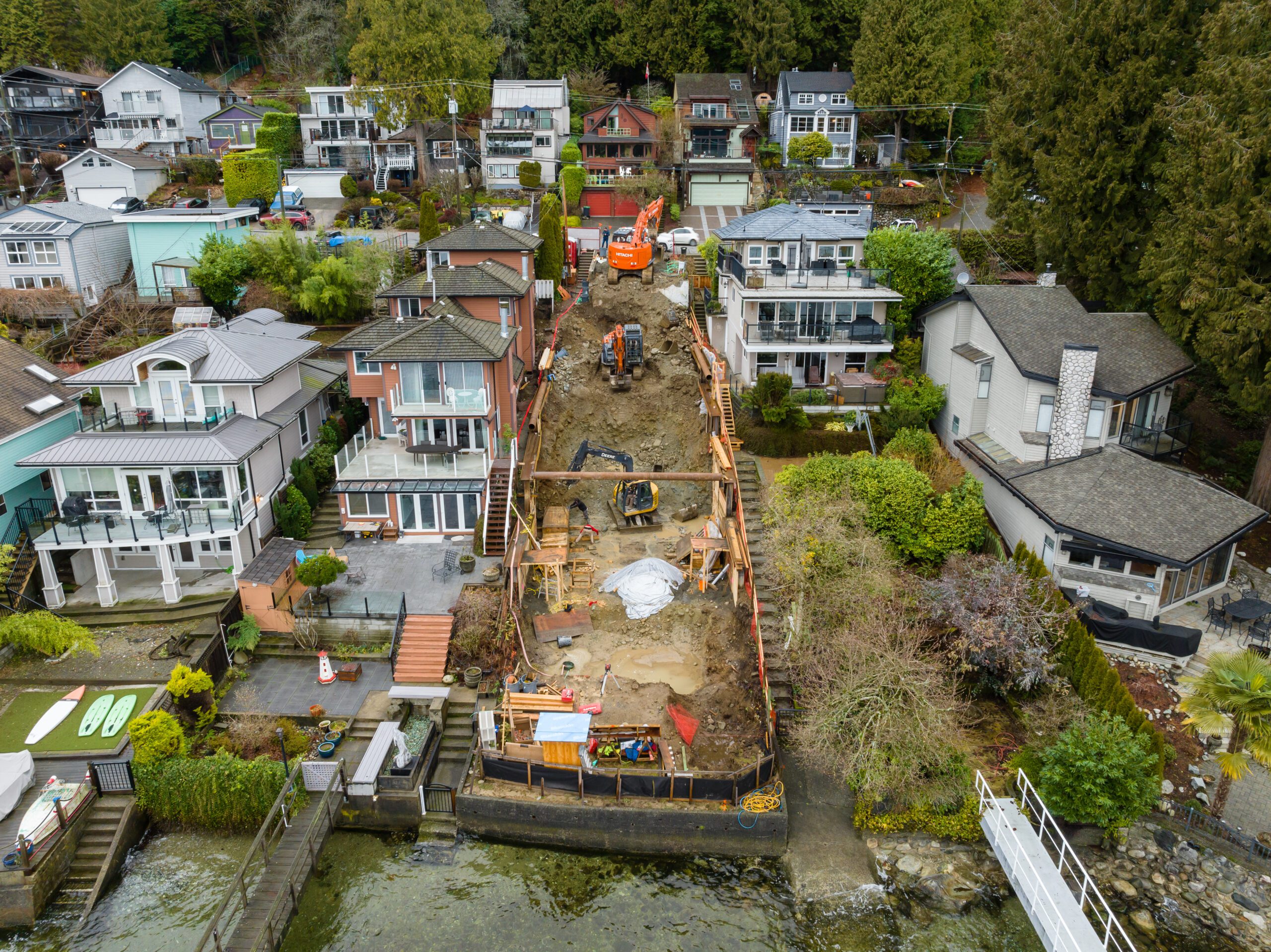 Excavators working on a steep waterfront lot during site preparation for the Fala custom home in North Vancouver.