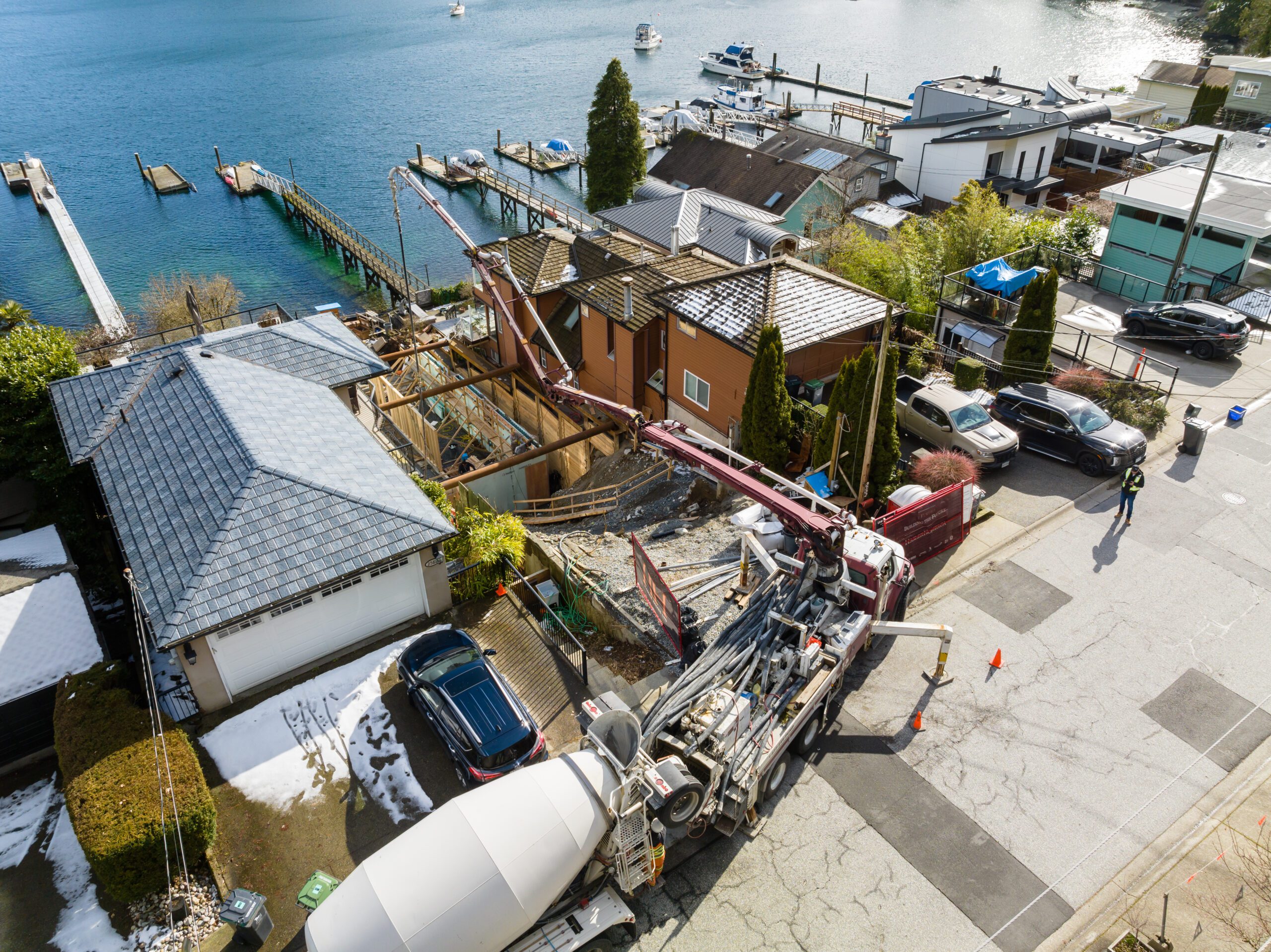 Concrete pump truck on a narrow residential street during construction of a home on a sloped lot in Deep Cove.